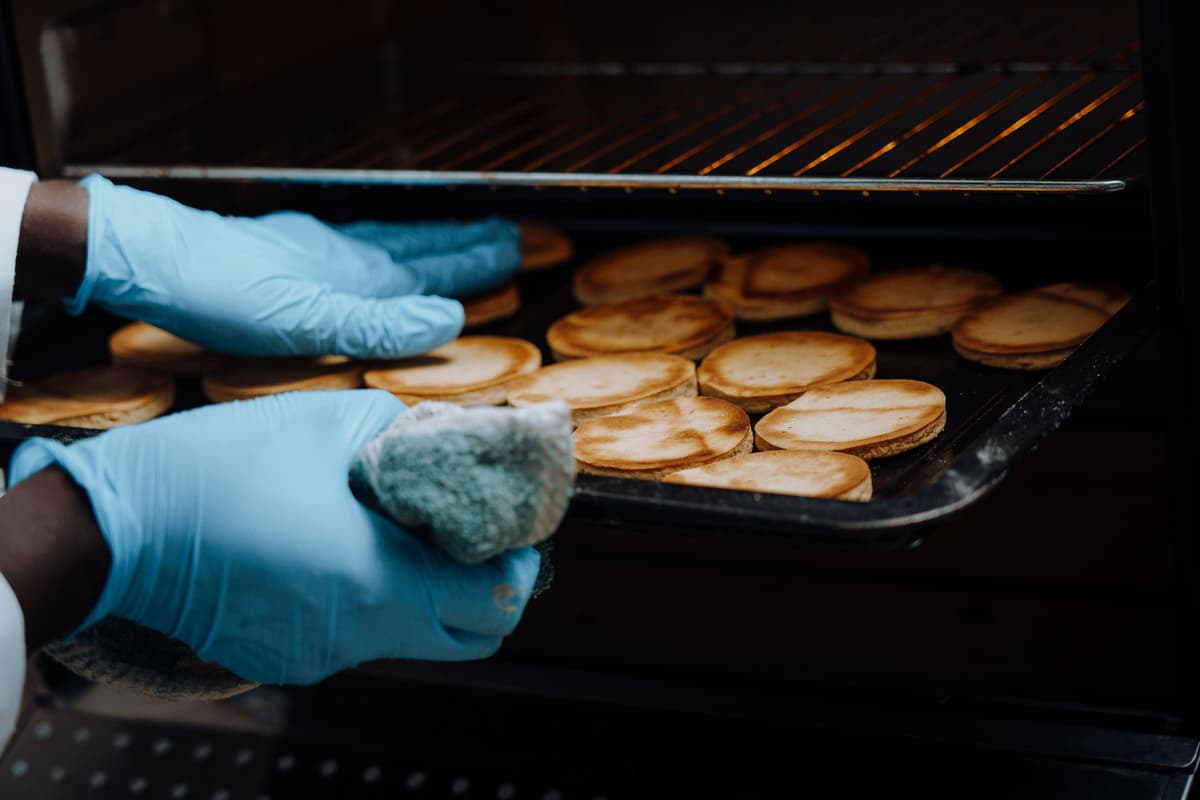 A chef dusting flour over a freshly prepared dough on a wooden board.