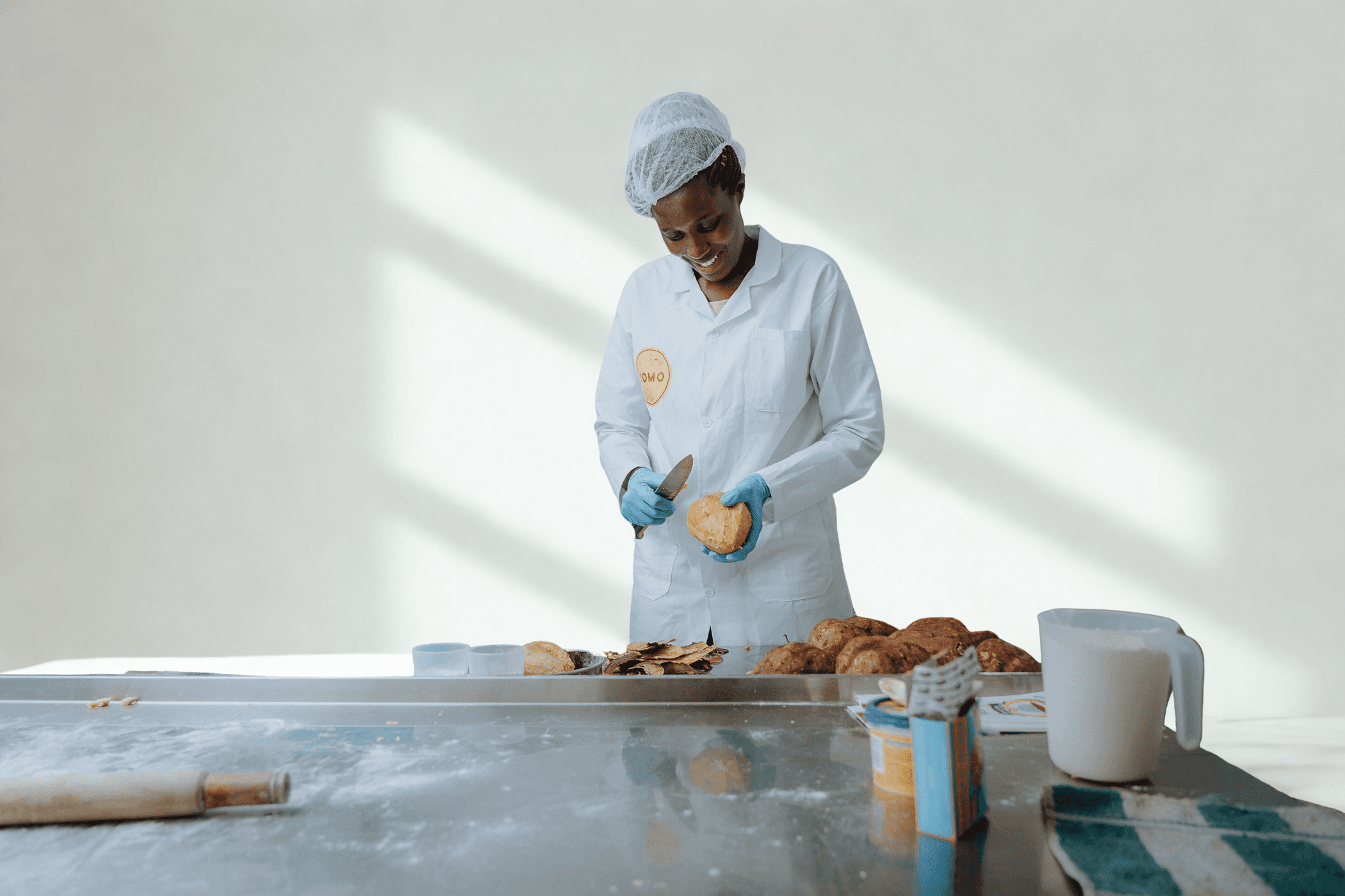 A chef standing on the right against a bright, whitish kitchen background, with empty space on the left.